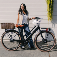 A woman stands next to a black Lekker Jordaan Urban steph through electric bike.