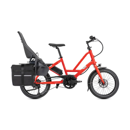 A red Tern Quick Haul cargo bicycle with a black child seat, rear pannier bag, and front suspension, shown from a side profile on a white background.